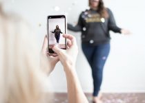 Photo by Amanda Vick person holding white smartphone taking photo of woman wearing blue jeans